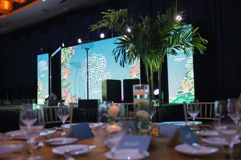 The BLUE Missions Gala main stage framed with tropical palms and dining tables